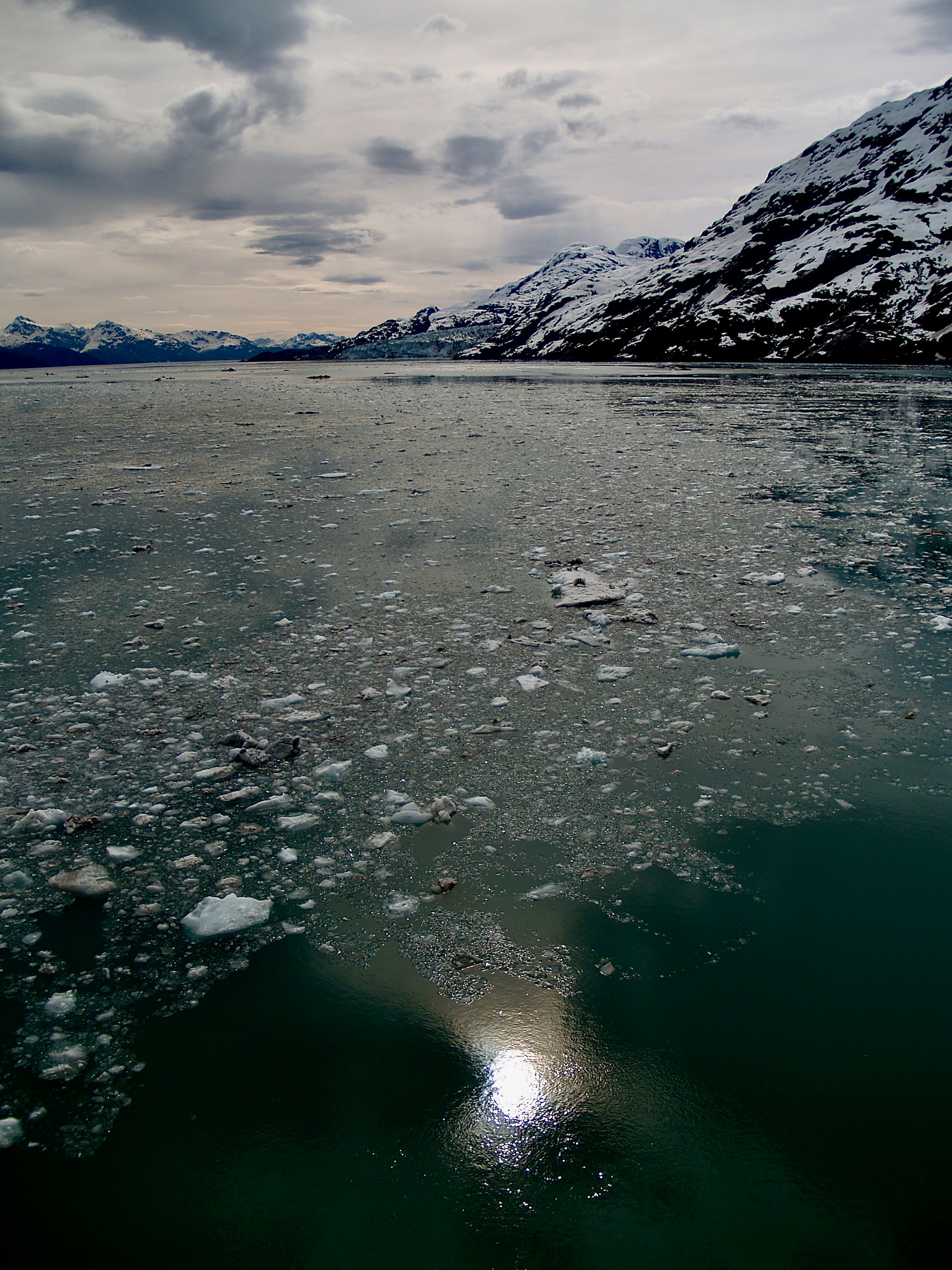 body of water near mountain under cloudy sky during daytime